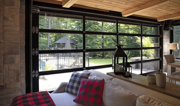 Une photo de l'intérieur du salon d'une maison scandinave ayant une porte de garage toute vitrée qui donne sur la piscine extérieure